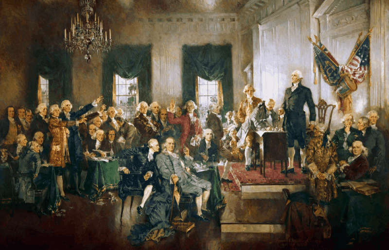 A historical painting depicting the signing of the U.S. Constitution, with delegates gathered around a table and one person standing and addressing the room.